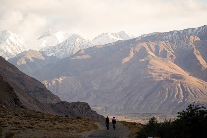 Two cyclists traveling through Tajikistan looking towards big mountains ahead