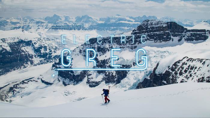 "Electric Greg" in neon lightbulb font over a picture of Greg hill skinning across wide snowy mountain