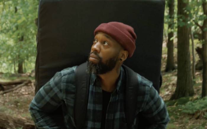 climber Raheim Robinson carrying boulder pad on back, wearing red beanie