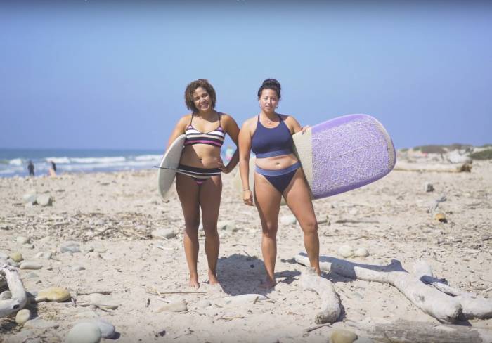 Danielle Lyons and another female surfer carrying surfboards