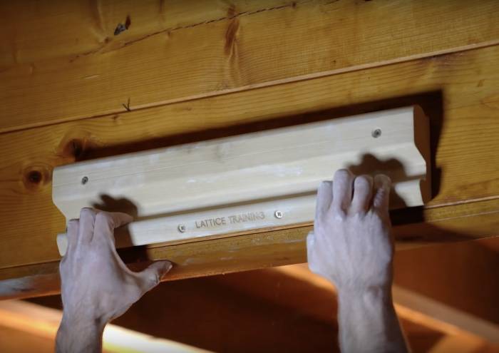climber's hands gripping the lattice training wood tool with small edge