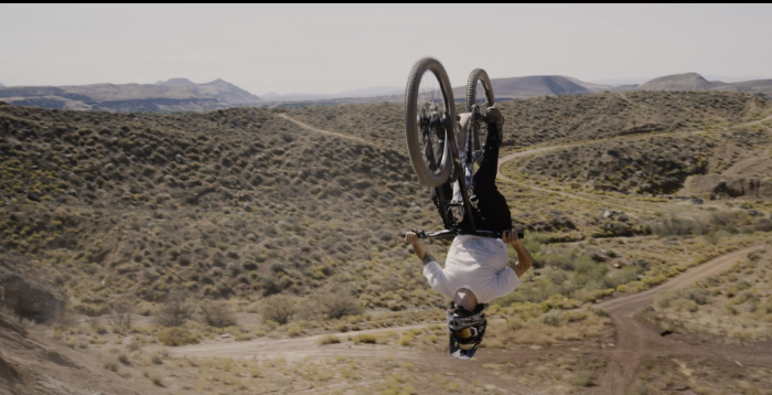 man on bike upside down in air with desert landscape in background