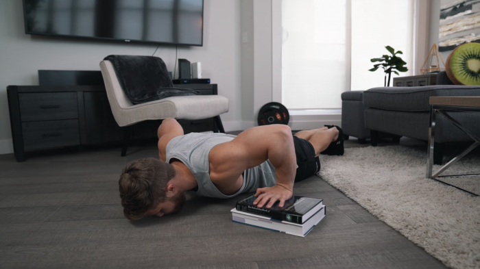 powerlifter does pushups on stack of books at home