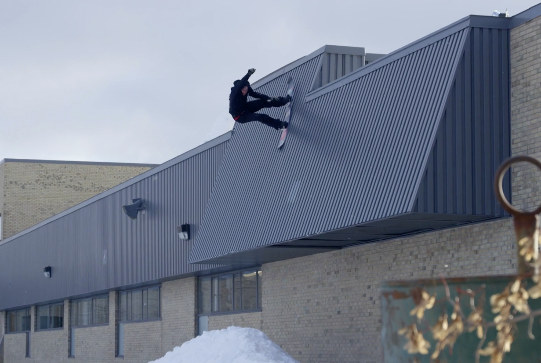 Craig McMorris snowboarding off a roof