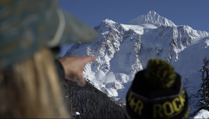 Cody Townsend's hand pointing towards snowy peak