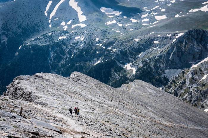small people in distance trekking across rocks in Greece