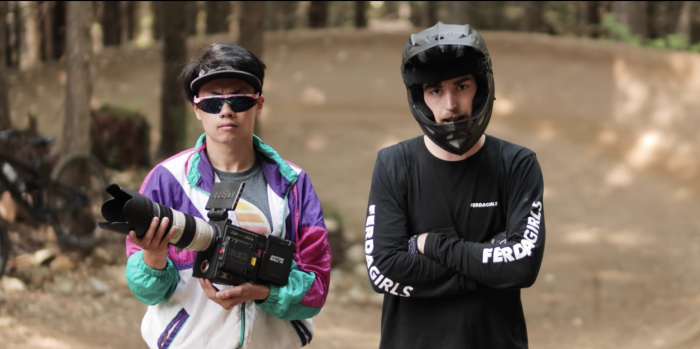 two bike park rats in helmets with film camera standing on track