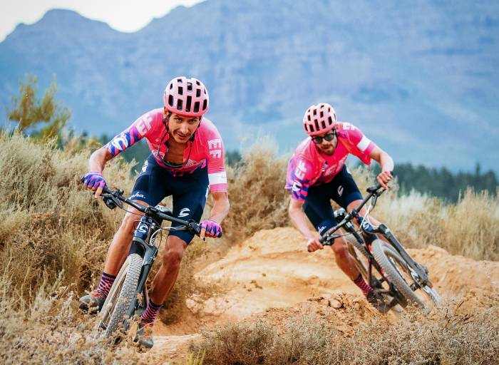 guys in matching pink jerseys and helmets biking on pump track