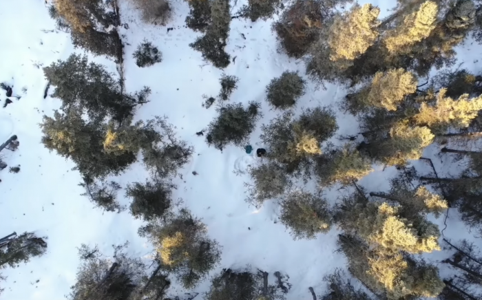 Drone footage from above of lost hiker sheltering in snow