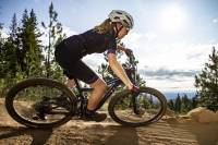 female mountain biking along dirt trail in grey vented Liv Rev pro helmet