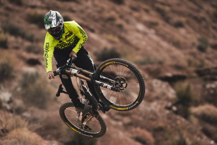 Cam Zink in helmet and neon jersey mountain biking in Utah