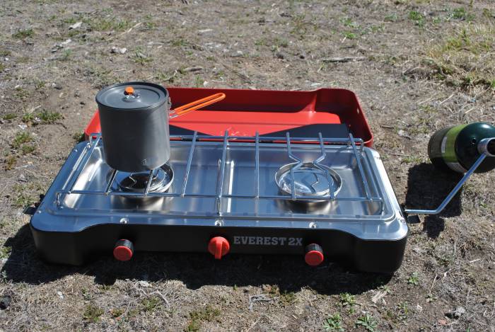 Camp Chef everest 2x stove with a small pot and propane burner set up on the ground