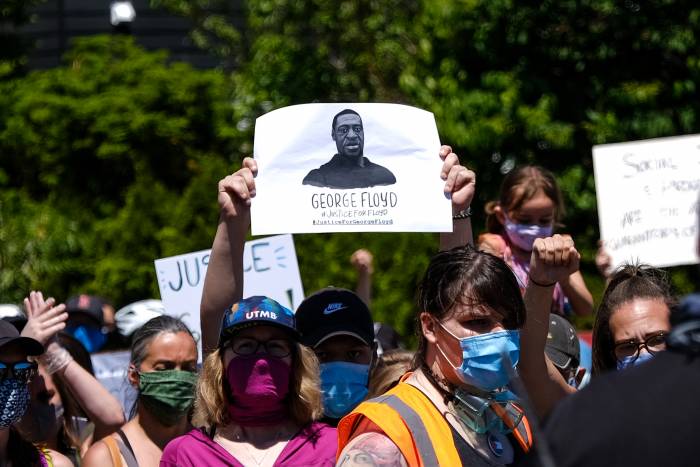 person holding a sign with a black and white photo drawing of George Floyd at a Minneapolis protest