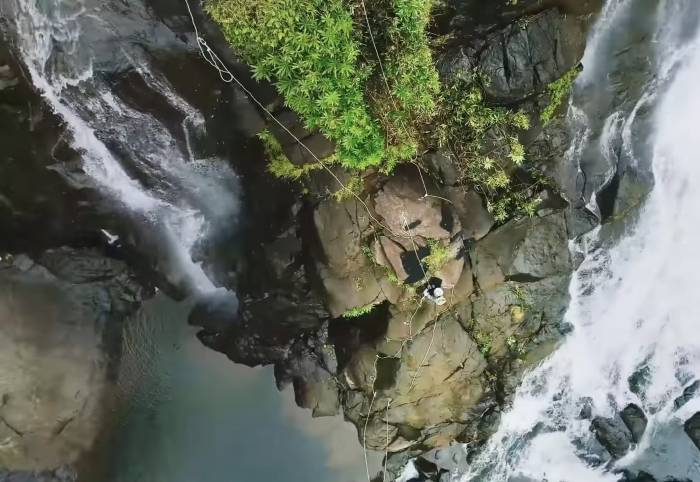 climber on rope course up side of waterfall in Fiji