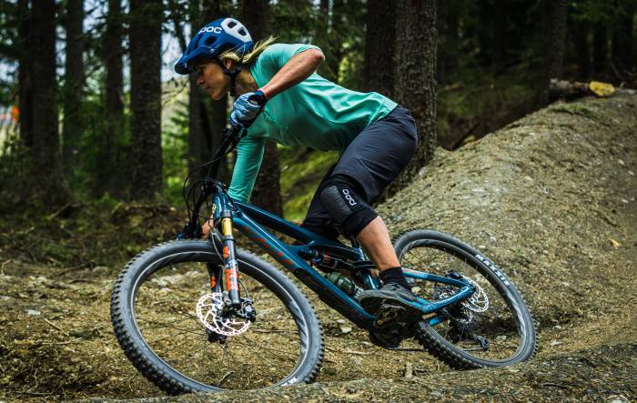 female in short sleeve jersey and knee pads riding ibis mojo v4 bike