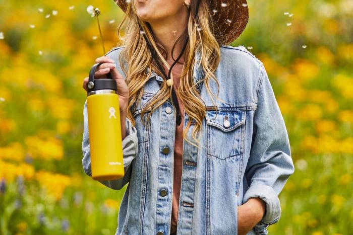Holding-a-yellow-Hydro-Flask-water-bottle-blowing-a-dandelion1