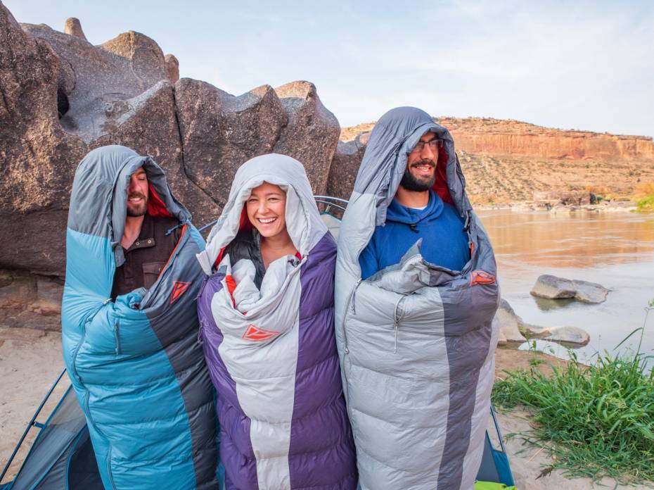 The Bestselling Gear at REI This Week 3 people wrapped up in sleeping bags, standing in a canyon outside