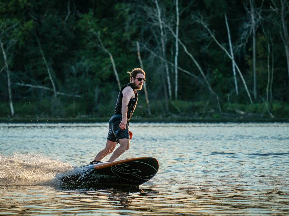 Guy riding the YuJet electric surfer surfboard on a lake
