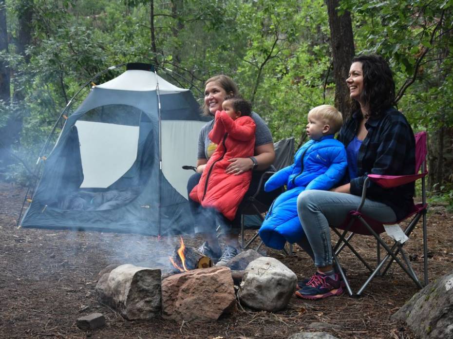 Parents and kids camping while the babies wear the Little Mo 40 degree Synthetic Baby Sleeping Bag