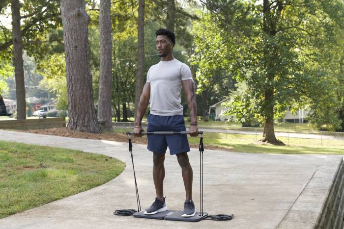Black man pulling up on bar attached to resistance bands with Evo Gym