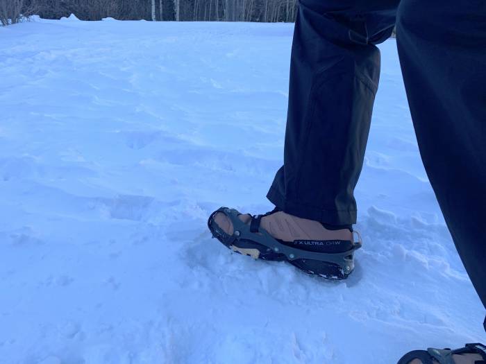 hiker taking a step in packed snow wearing the hillsound equipment flexsteps spikes