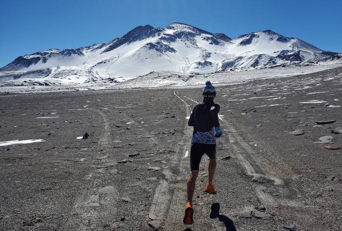 tyler andrews running towards mountain volcano