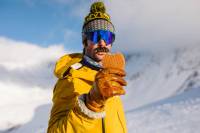 Skier in yellow jacket holding up Honey Stinger Short Stack Waffle snack