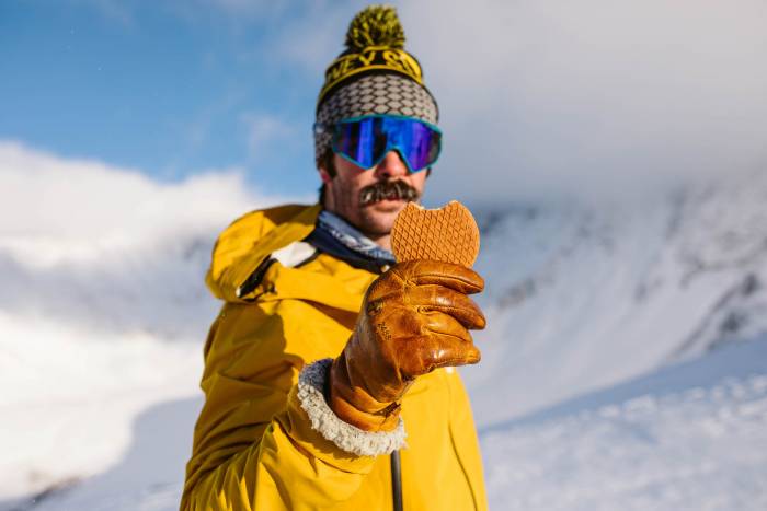 Skier in yellow jacket holding up Honey Stinger Short Stack Waffle snack