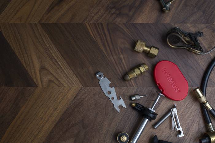 Primus stove parts and repair tools scattered on table