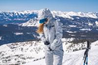 Down With DWR: Helly Hansen Debuts Chemical-Free Backcountry Kit for Women Female zipping up the Helly Hansen white Pro Shell, wearing a hat and hood