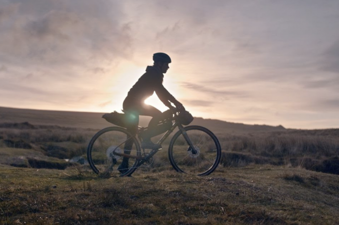 cyclist biking across flat trail at pink sunset