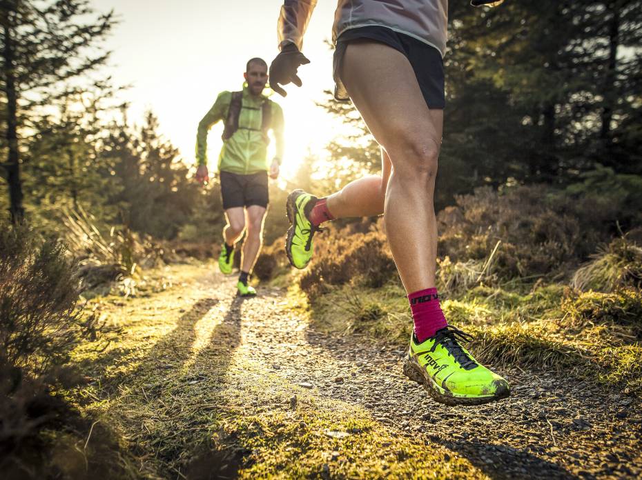 Next-Level Cushion: inov-8 Drops G-Fly, First Graphene-Enhanced Foam two runners running down trail with sun setting in background