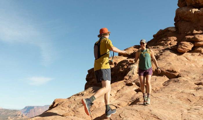 two hikers in short sleeves and keen boots hiking over rocky terrain