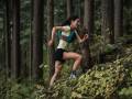 runner rachel drake running uphill on forest trail
