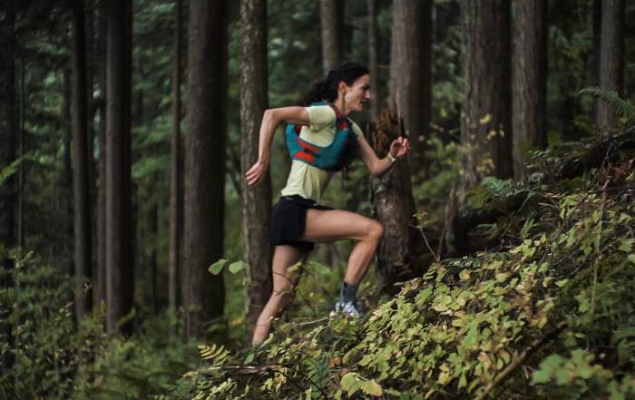 runner rachel drake running uphill on forest trail