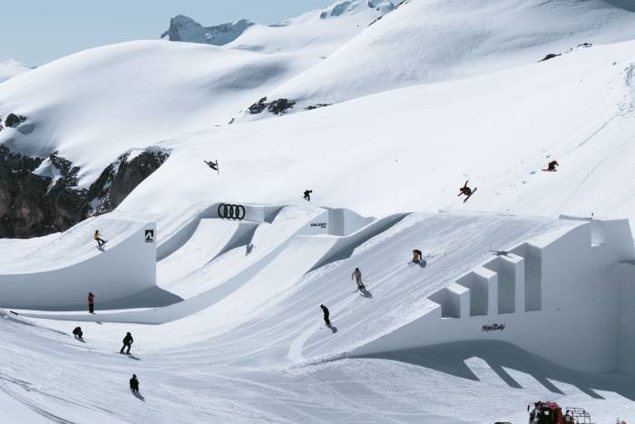 skiers riding in a line across features in swiss alps