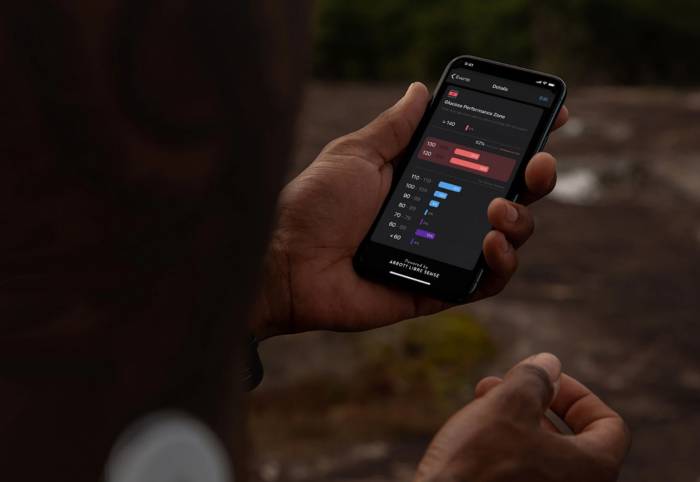 glucose monitoring biosensor on man's arm and the app on smartphone screen