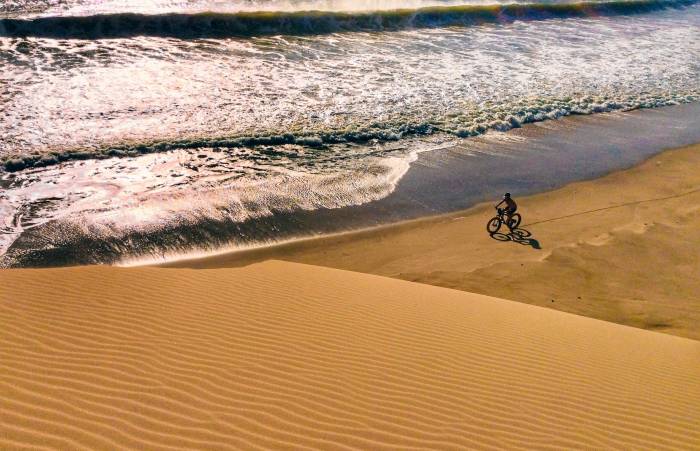 Kate Lemming cycling across a Namibia desert beach