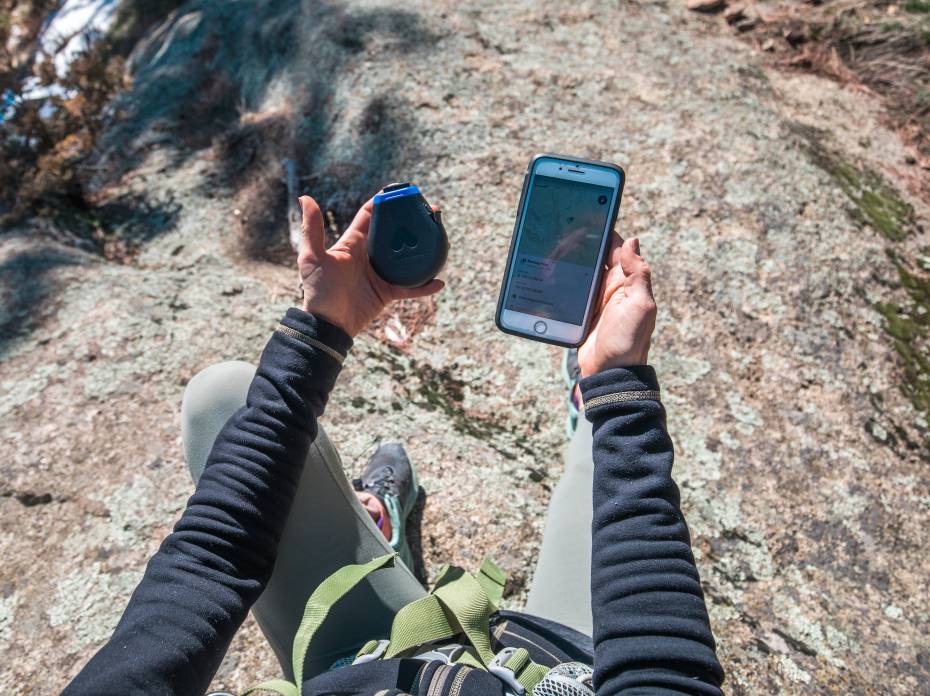 Somewear Labs and onX Partner to Launch First Sat-Connected Waypoints hiker holding a Somewear hotspot and smartphone while sitting on a rock