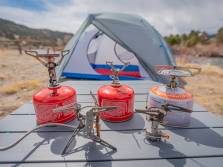 The Best Backpacking Stoves of 2021 five different lightweight backpacking stoves with fuel canisters and a tent in the background