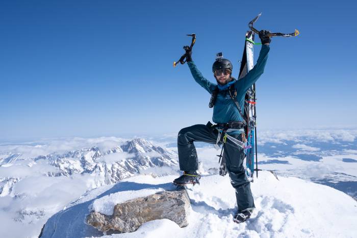 santi vega standing on the summit of the grand teton with ice axe in the air