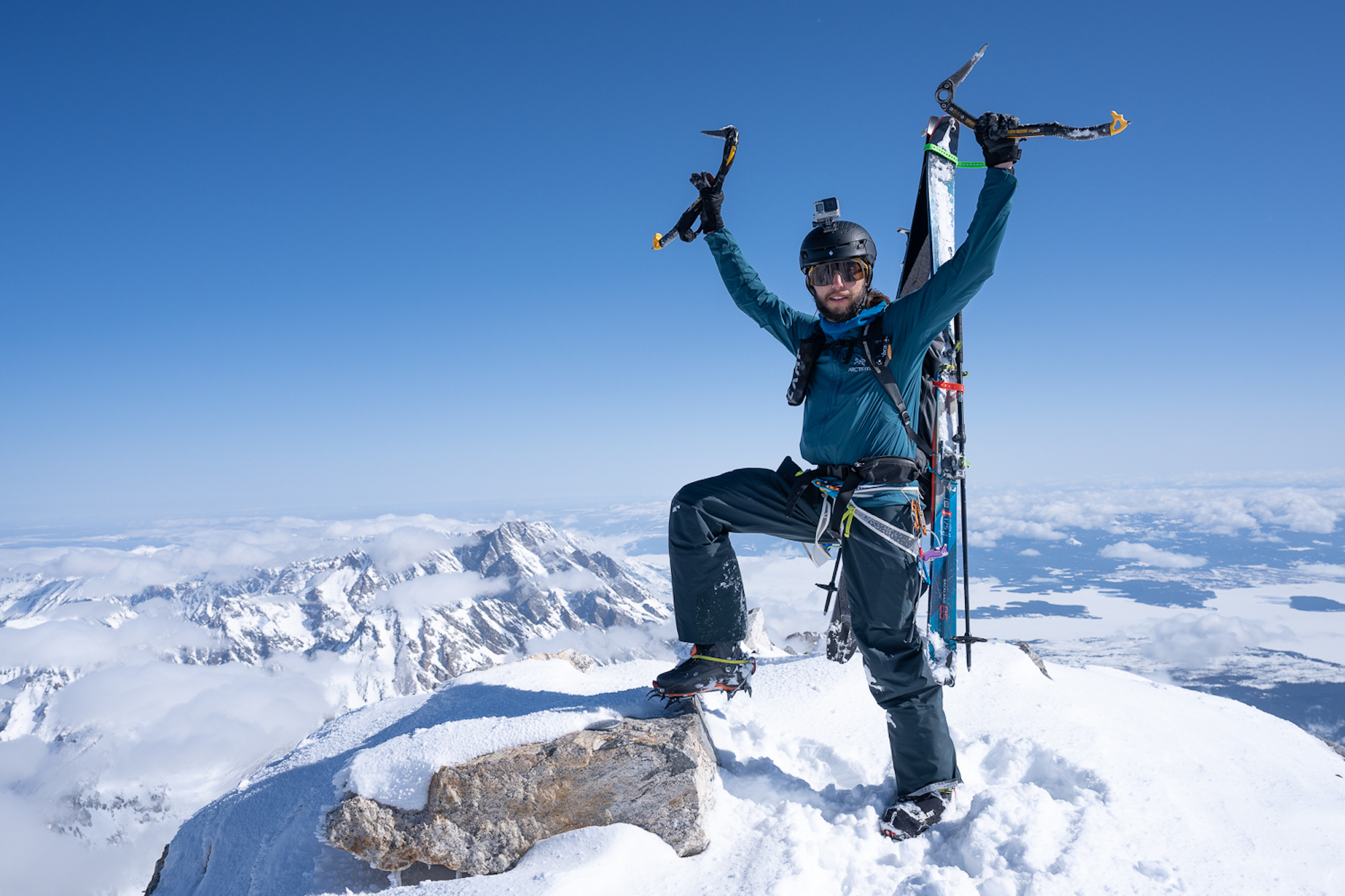 santi vega standing on the summit of the grand teton with ice axe in the air