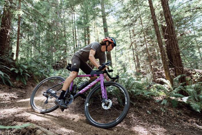 man in spandex shorts and gray shirt riding canyon Grizl gravel bike down a trail