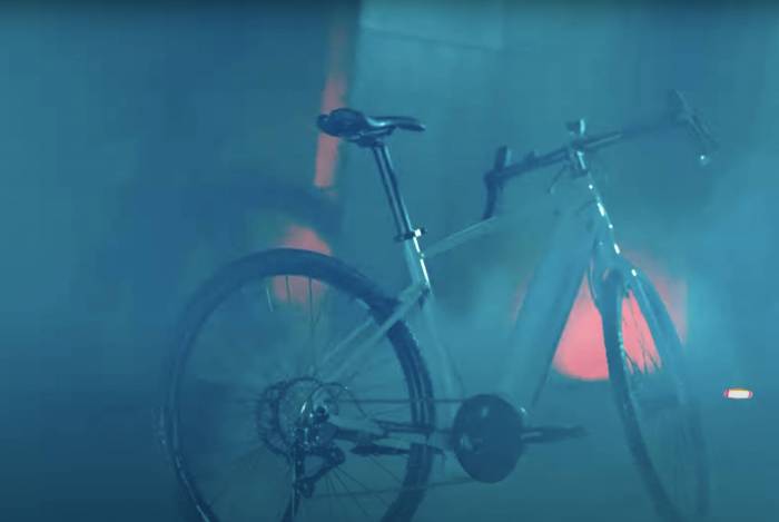 smoky, blurry view of a diamondback blue e-bike against a concrete wall