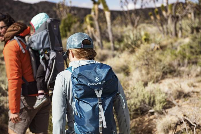 woman with blue pack and man with child carrier hiking in desert