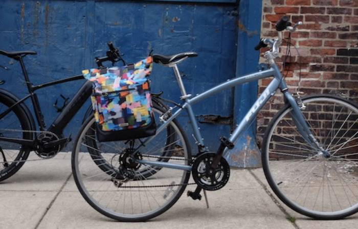 colorful pannier bike bag on women's cruiser by a blue brick wall