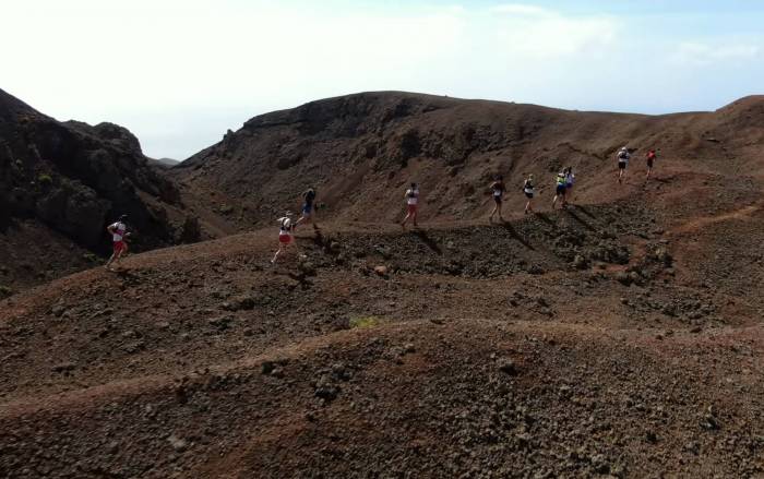 a line of six runners along a desert island ridge
