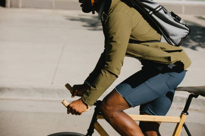 man in olive shirt jacket and navy shorts riding bike