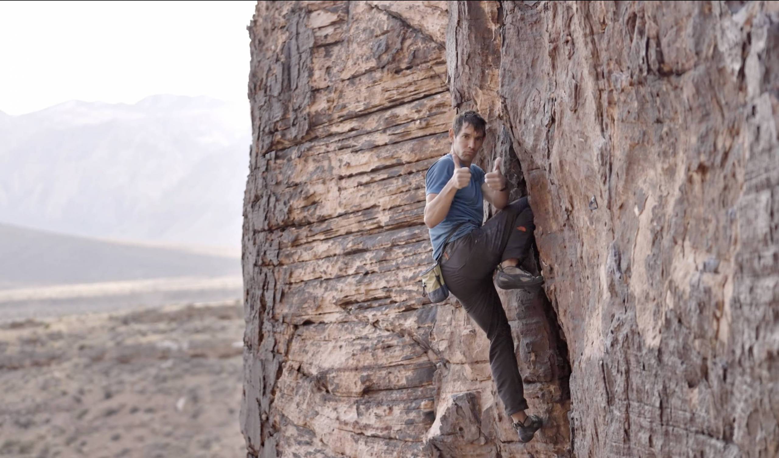 alex honnold employing a knee bar so he can give the camera a two thumbs up