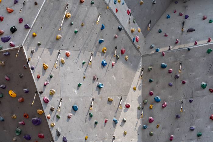 gym climbing wall scattered with holds and draw clips